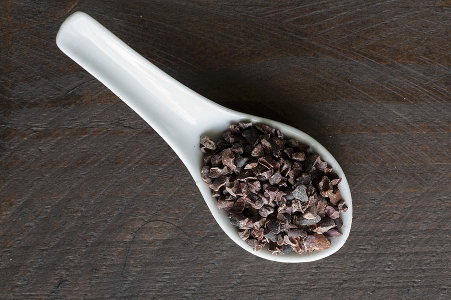 Cocoa Nibs On A Porcelain Spoon On A Dark Surface Photograph by Nicole Godt