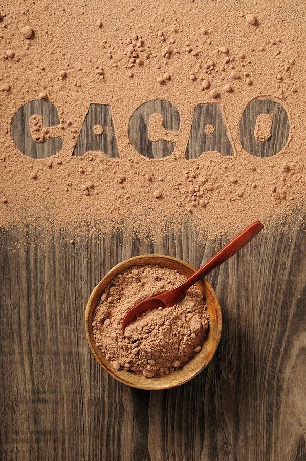 Cocoa Powder In A Bowl And Spilled On A Wooden Background With The Word cacao Photograph by Jean-christophe Riou