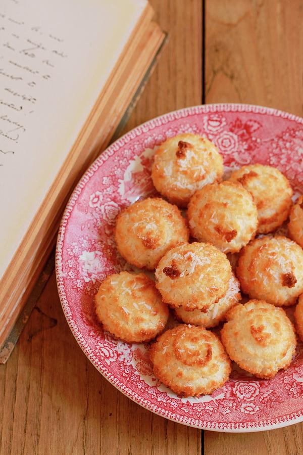 Coconut Macaroons On A Plate Next To A Book Photograph by Carmen Mariani