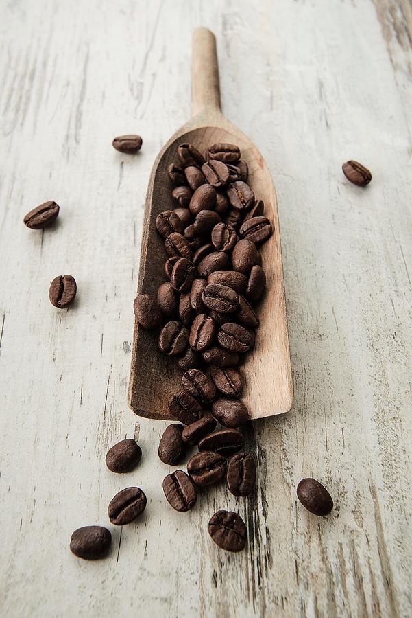 Coffee Beans On A Scoop On A Light Wooden Surface Photograph by Julian Winkhaus