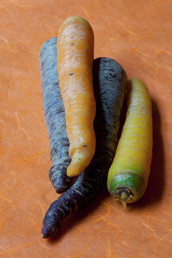 Coloured Carrots On Orange Paper Photograph by Hilde Mche
