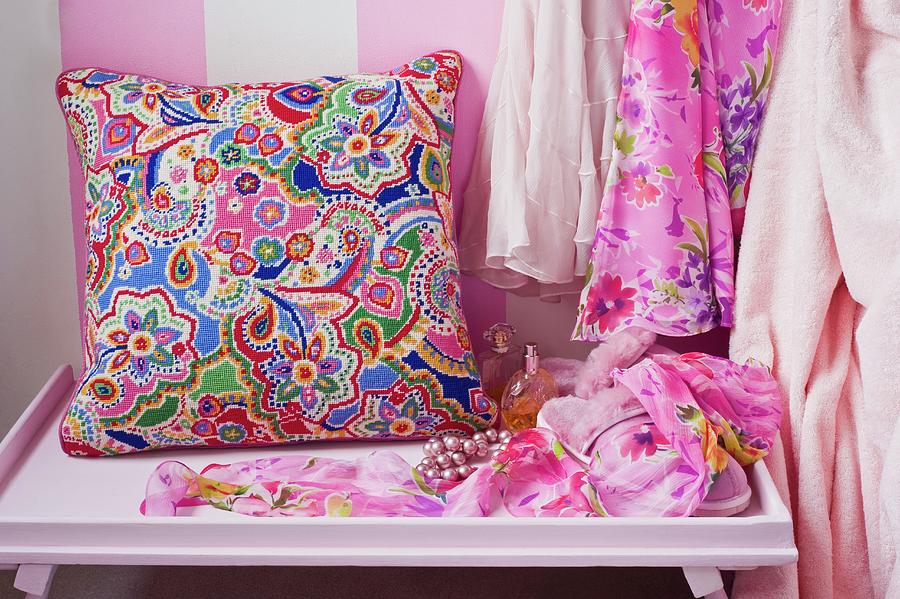 Colourful, Ethnic-style Cushion On Console Table Next To Dresses Hanging Up Photograph by Linda Burgess