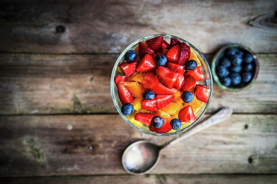 Colourful Fruit Salad In A Jar On Rustic Wooden Surface Photograph by Alena Haurylik