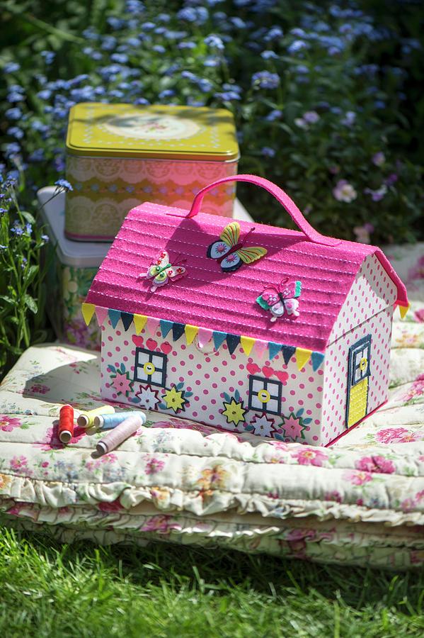 Colourful, House-shaped Sewing Box On Floral Floor Cushion In Garden Photograph by Winfried Heinze