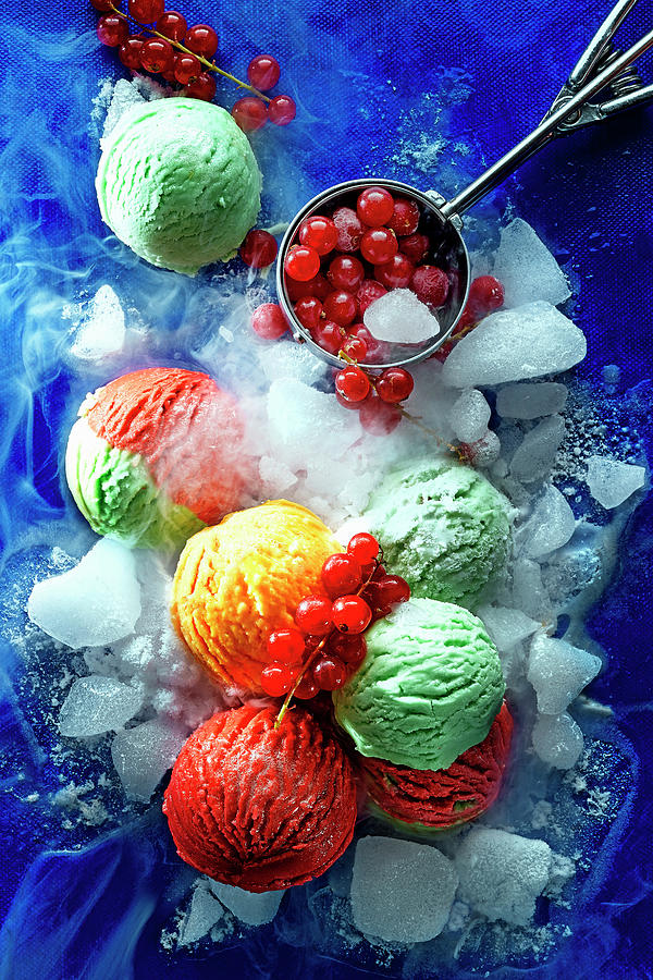 Colourful Scoops Of Ice Cream With Ice Cubes And Redcurrants On A Blue Surface Photograph by Manfred Rave