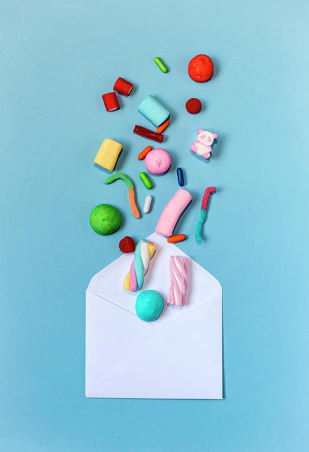 Colourful Sweets Coming Out Of An Envelope On A Light-blue Background Photograph by Eduardo Lopez Coronado