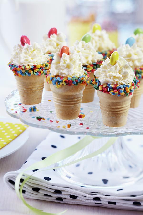 Cones Of Ice Cream Edged With Sugar Confetti And Decorated With Cream And Smarties Festively Arranged On Cake Stand Photograph by Franziska Taube