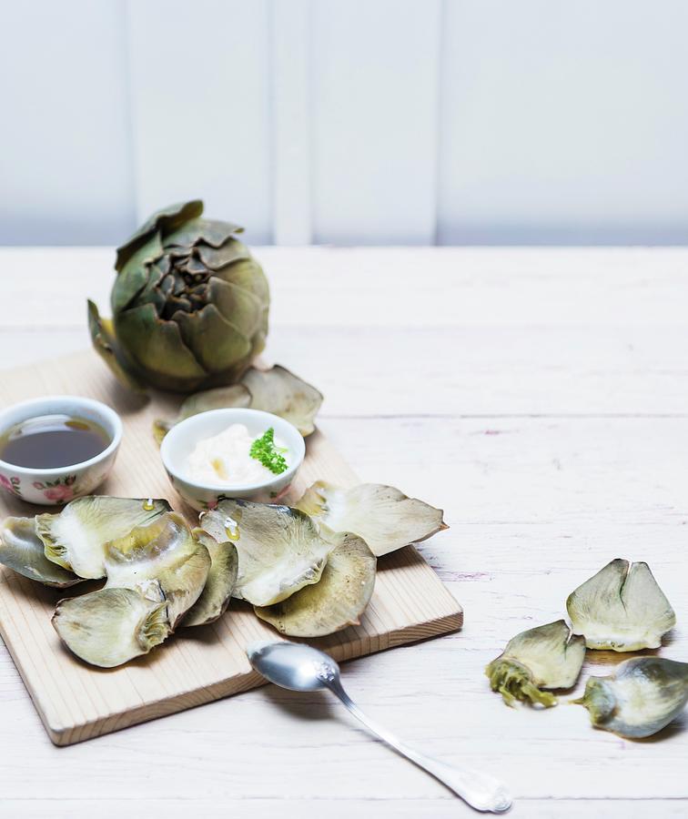 Cooked Artichokes On A Wooden Board With Aioli And Vinaigrette Photograph by Angelika Grossmann