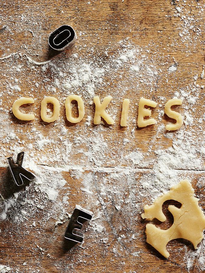 Cookie Dough, Cut-out Letters And Cutters On A Floured Wooden Surface Photograph by Amanda Stockley