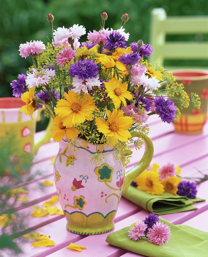 Coreopsis And Cornflowers In Jug On Garden Table Photograph by Friedrich Strauss