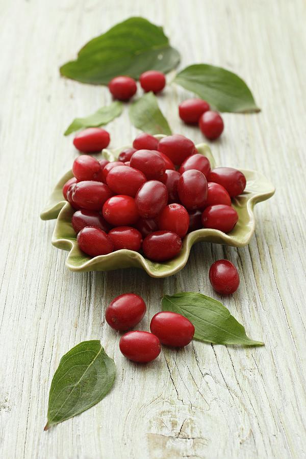 Cornelian Cherries With Leaves In A Bowl And Next To It Photograph by Petr Gross