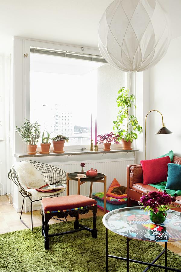 Corner Of Living Room With Stool, Side Tables, Colourful Tray, Green Flokati Rug, Spherical Pendant Lamp And Classic, Wire Chair Below Window Photograph by Ulrika Ekblom