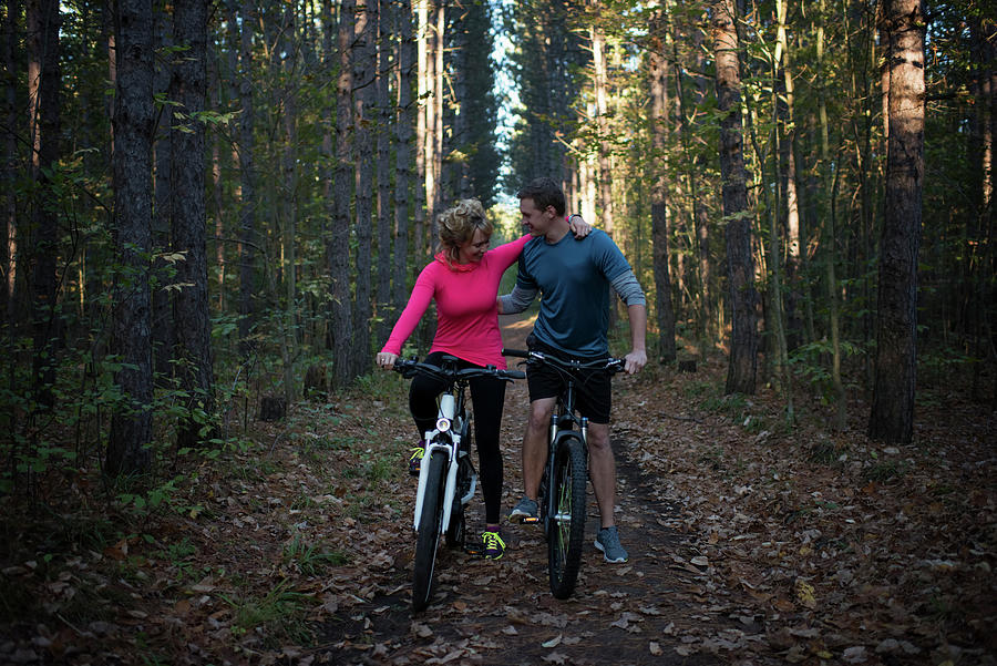 Tree Photograph - Couple Mountain Biking Together Against Trees In Forest by Cavan Images