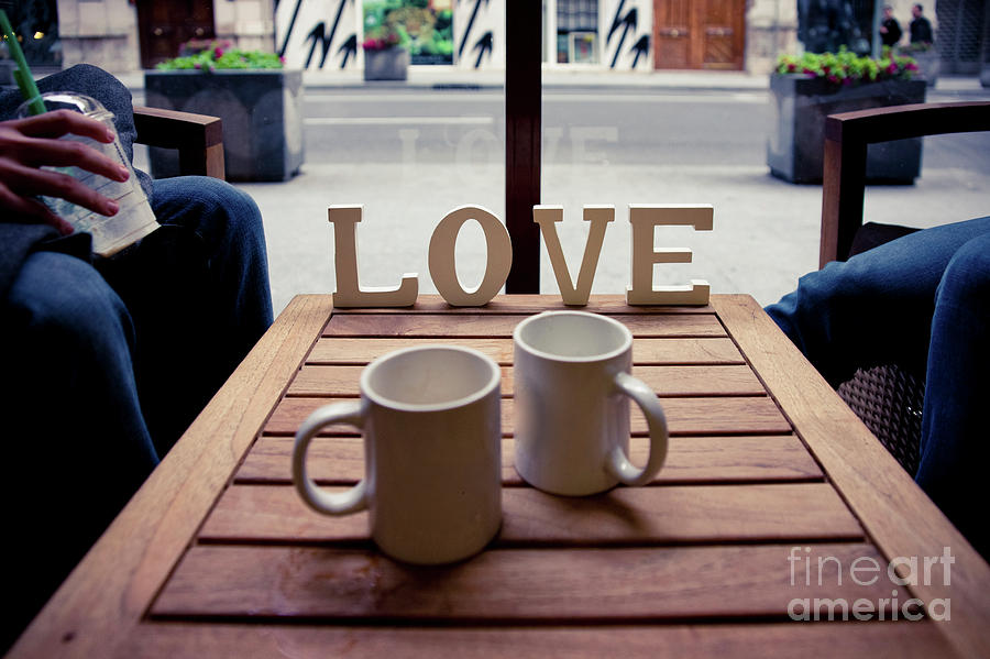 Couple Relaxing With A Coffee And Word Love On Wood. Photograph