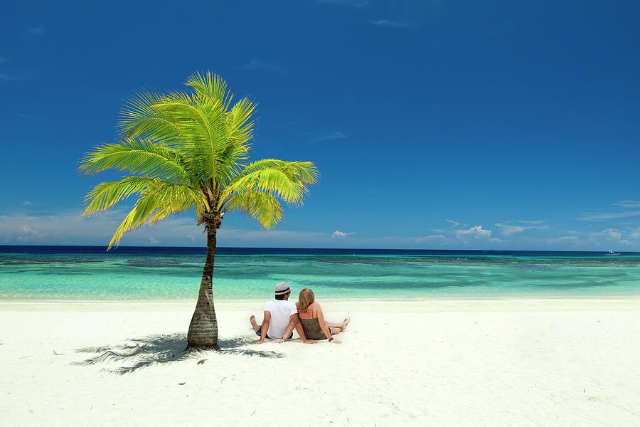 Couple Sitting On Tropical Beach Photograph by Dstephens