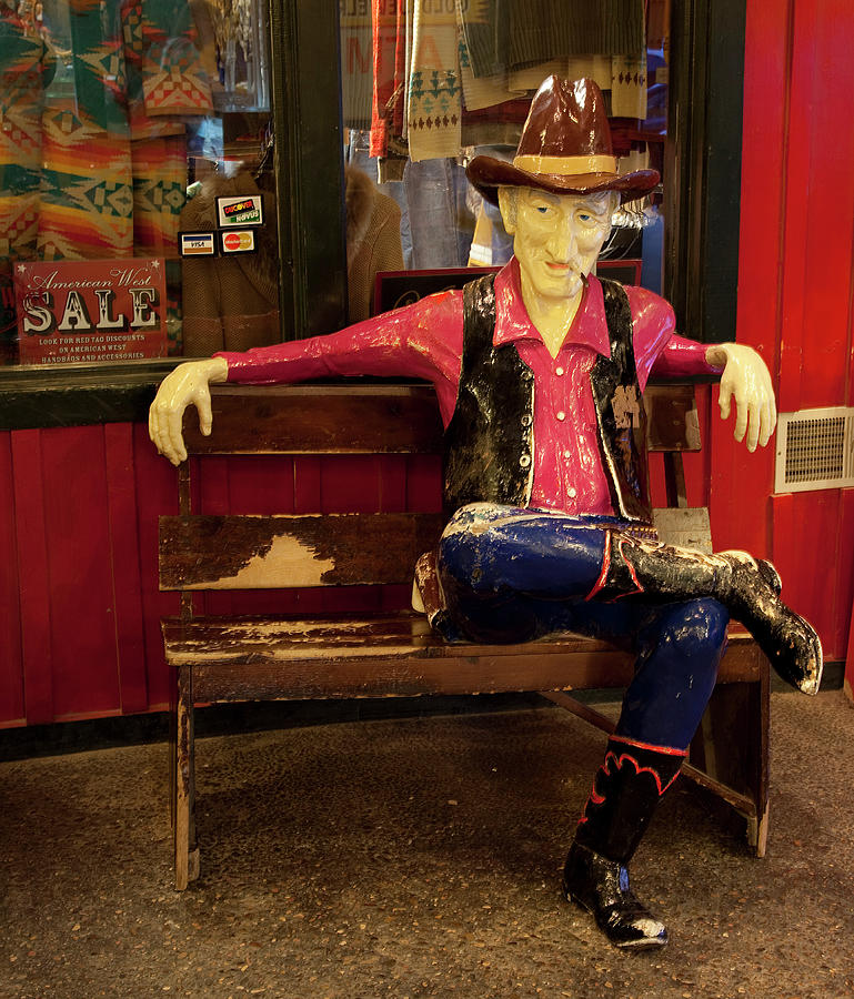 Cowboy sits on bench at Wall Drug in South Dakota Painting by 