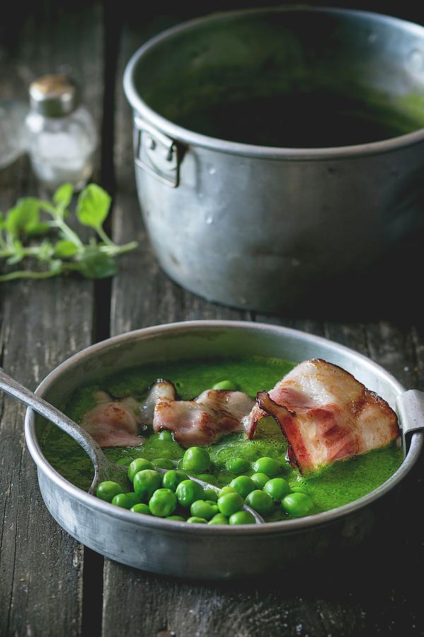 Cream Of Pea Soup With Fried Bacon On A Wooden Table Photograph by Natasha Breen