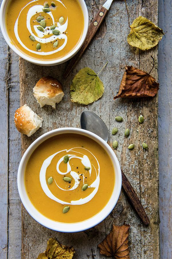 Creamy Pumpkin With Cream And Pumpkin Seeds On A Wooden Board Photograph by Magdalena Hendey