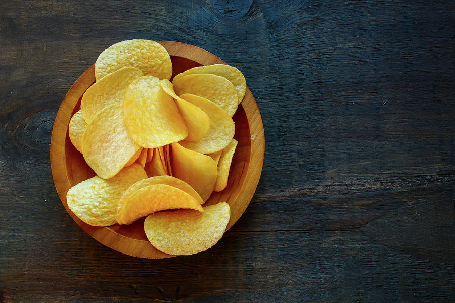 Crisps In A Wooden Bowl On A Dark Wooden Surface seen From Above Photograph by Yuliya Gontar