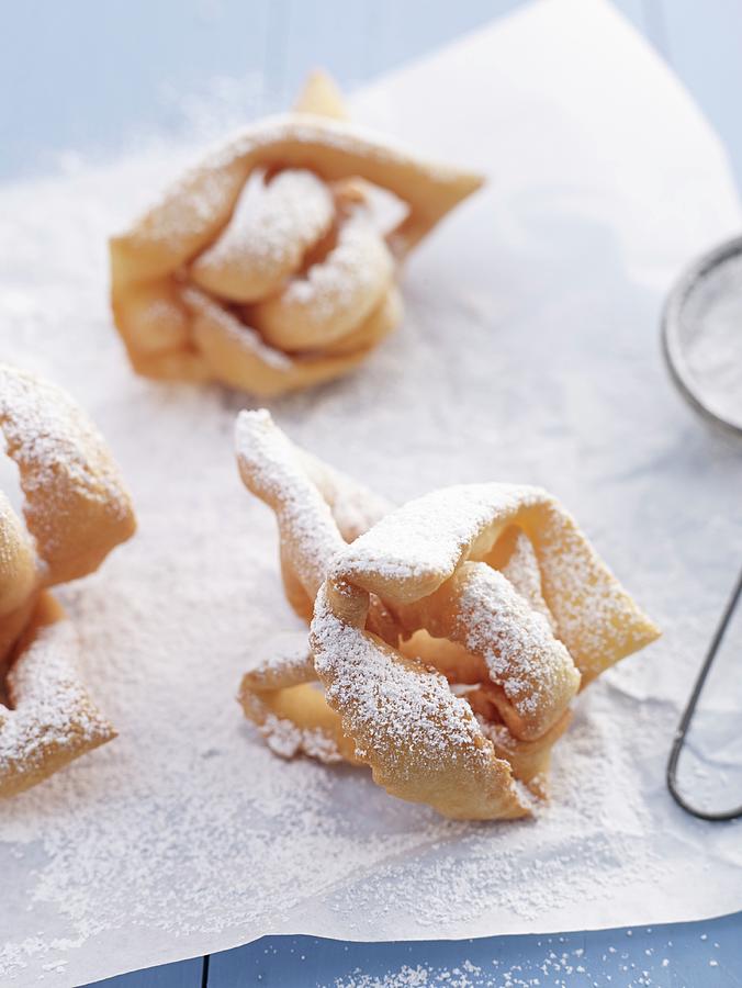 Crispy Fried Pasty With Icing Sugar On A Piece Of Baking Paper Photograph by Oliver Brachat