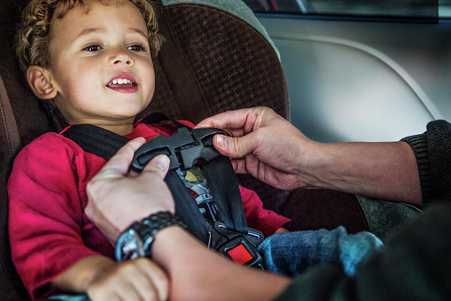 Cropped Image Of Father Buckling Son On Baby Seat Photograph by Cavan ...