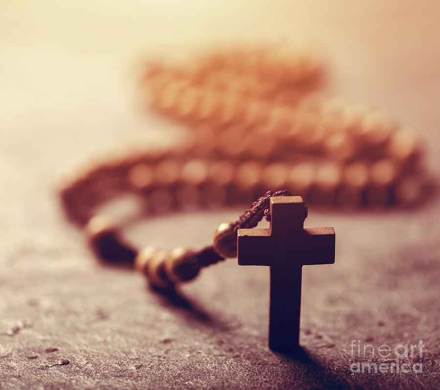 Cross and wooden rosary on stone background. Photograph by Michal Bednarek