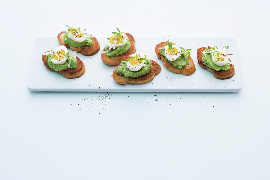 Crostini Topped With Pea And Avocado Cream And Quails Eggs Photograph by Michael Wissing