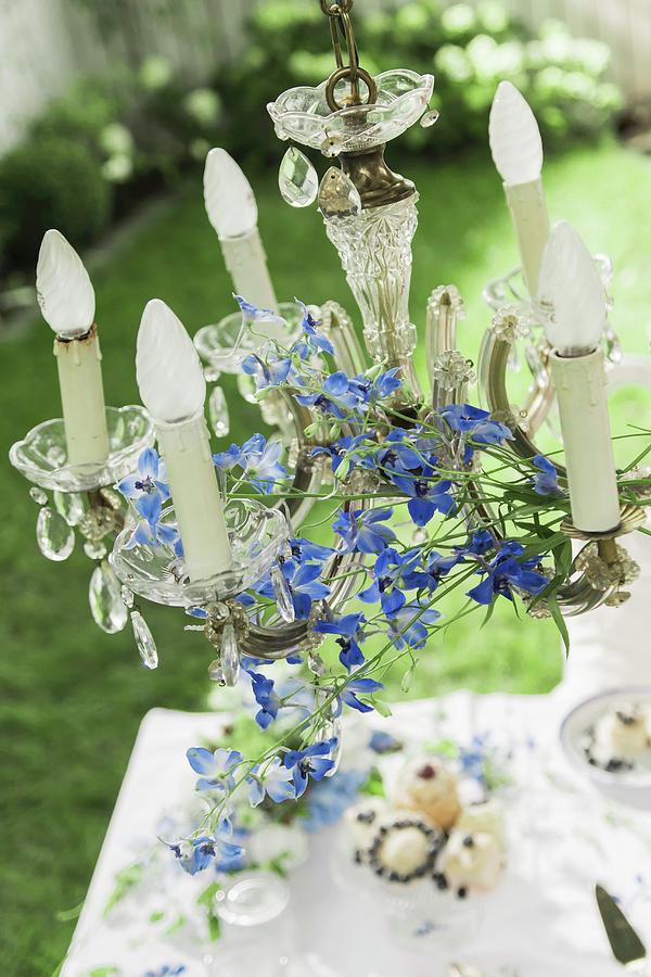 Crystal Chandelier Decorated With Delphiniums Hung Over Coffee Table In Garden Photograph by Bildhbsch