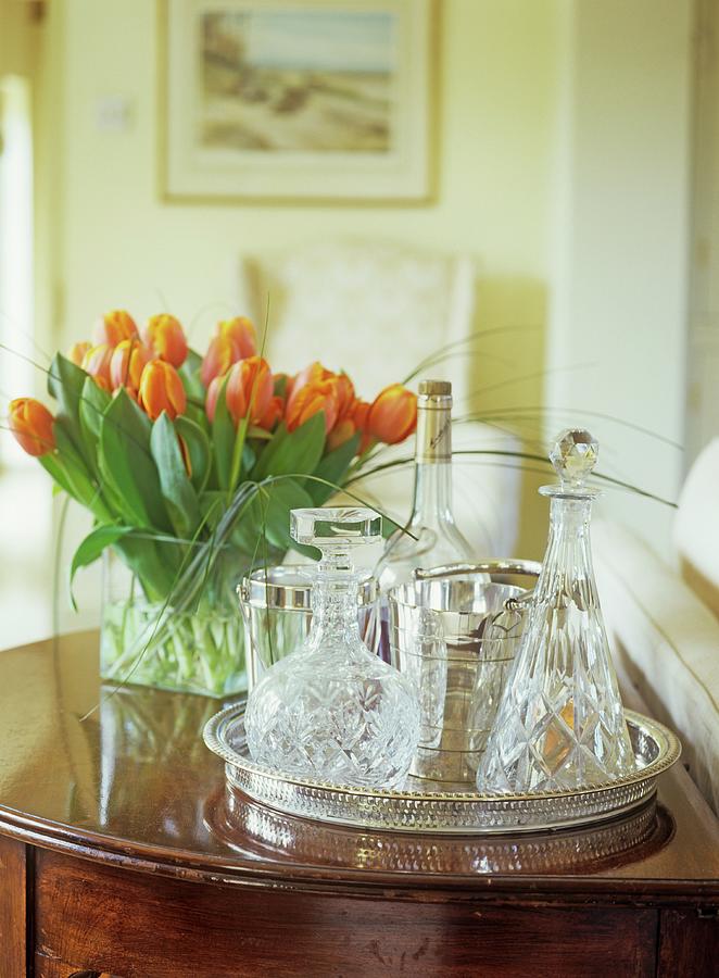 Crystal Decanters On Silver Tray Next To Bouquet Of Orange Tulips Photograph by Winfried Heinze