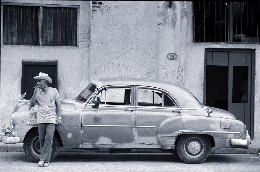 Cuban Man Leaning Against Car Smoking Photograph by Peter Adams