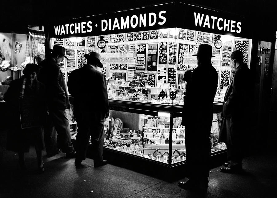 New York City Photograph - Customers peering at the wares inside a small, brightly lit Times Square jewelry & watch shop. by Peter Stackpole