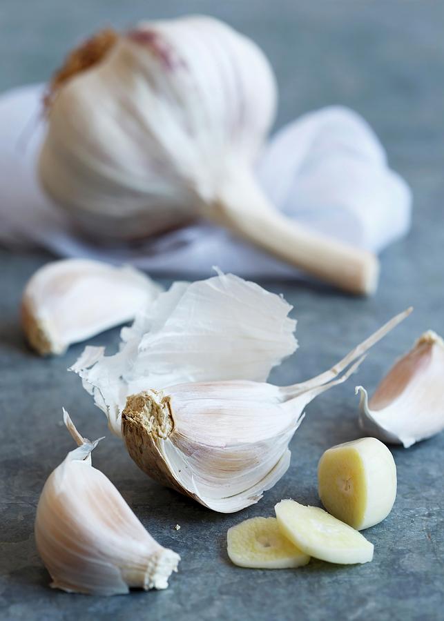 Cut Up Clove Of Purple Stripe Garlic With Unpeeled Cloves Lying On A Blue-grey Sheet Metal Photograph by Etienne Voss