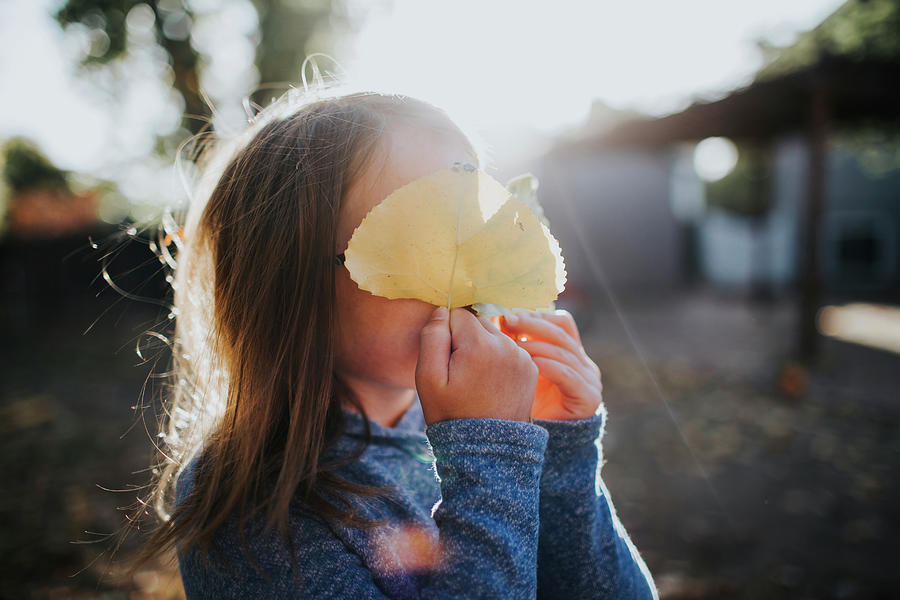 Cute Girl Hiding Face With Leaves On Sunny Day Photograph by Cavan ...