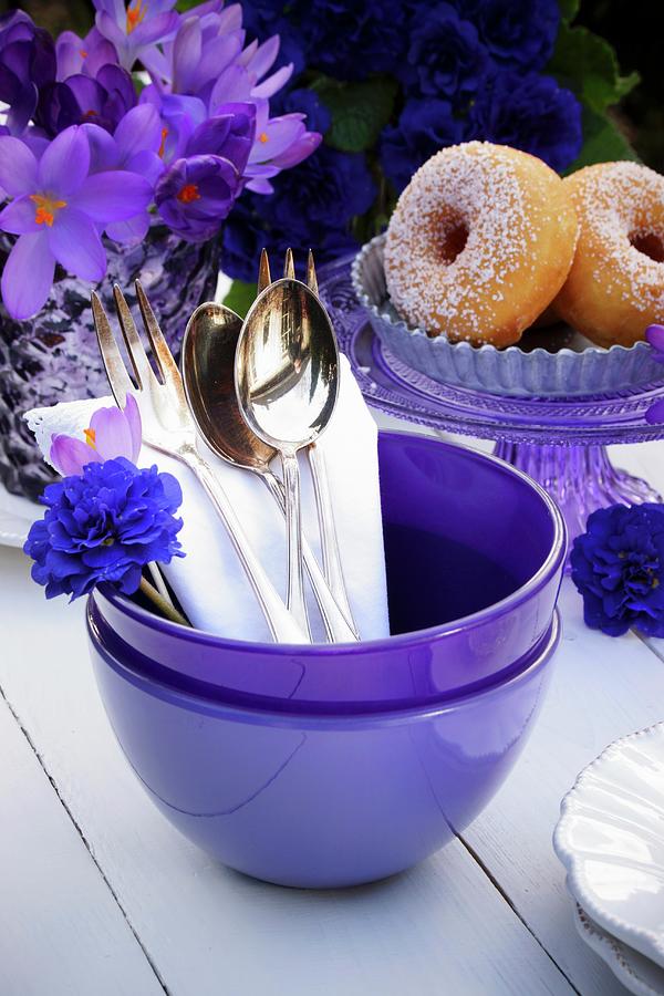 Cutlery In A Purple Bowl With Doughnuts And Purple Spring Flowers In The Background Photograph by Angelica Linnhoff