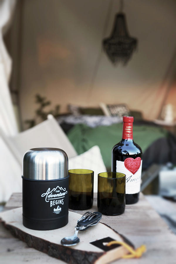 Cutlery, Thermos Flask, Glasses And Bottle Of Red Wine On Wooden Table Outside Tent Photograph by Annette Nordstrom