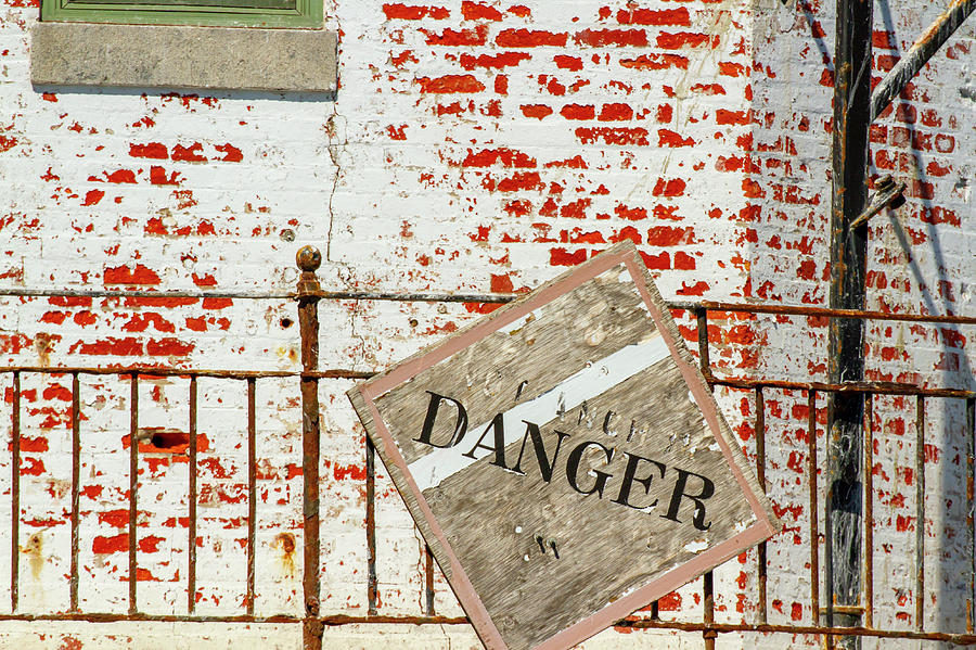 Danger sign on rusty banister on grunge brick wall Photograph by Karen Foley