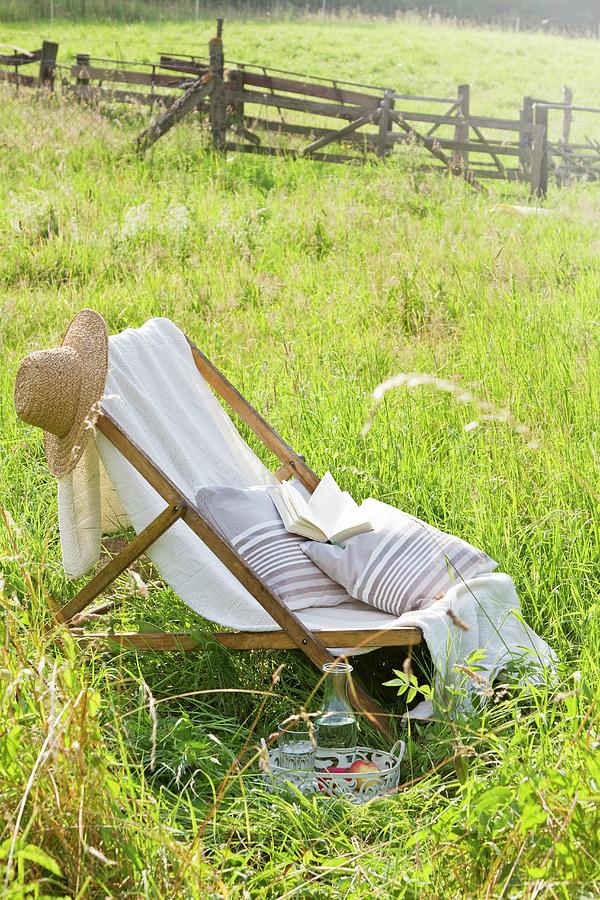 Deckchair, Straw Hat, Cushions And Book In Summer Meadow Photograph by Catja Vedder
