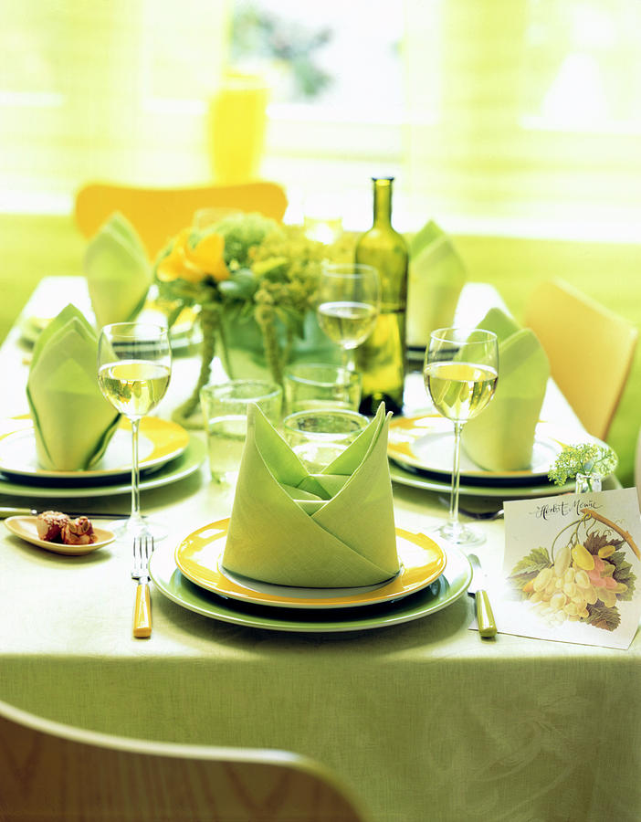 Decorated Table With Green Table Cloth And Folded Napkins On Plates