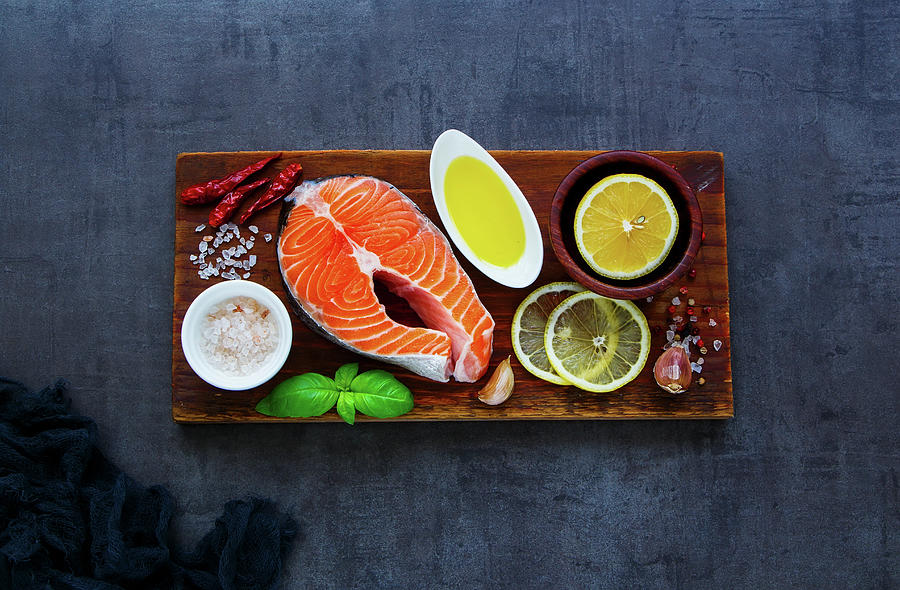 Delicious Uncooked Salmon Fish Steak With Lemon, Oil, Herbs And Spices On Rustic Wooden Chopping Board Over Dark Concrete Background Photograph by Yuliya Gontar