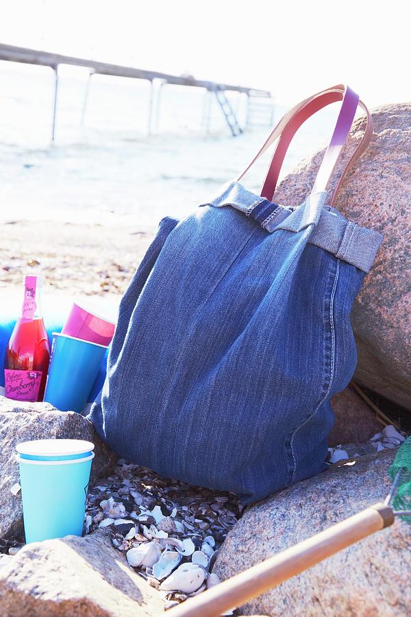 Denim Bag And Colourful Beakers On Beach Photograph by Greenhaus Press