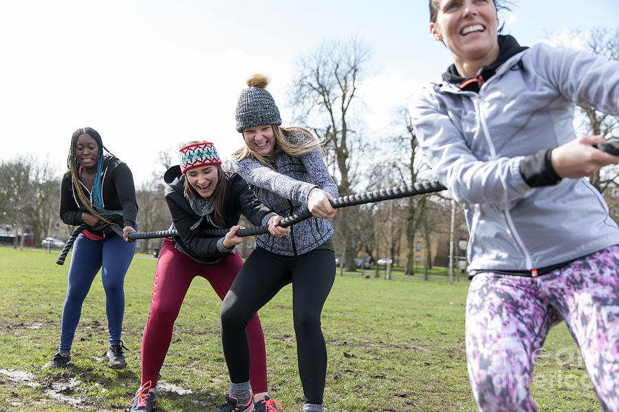 Determined Women Pulling Rope In Tug Of War In Sunny Park Photograph By