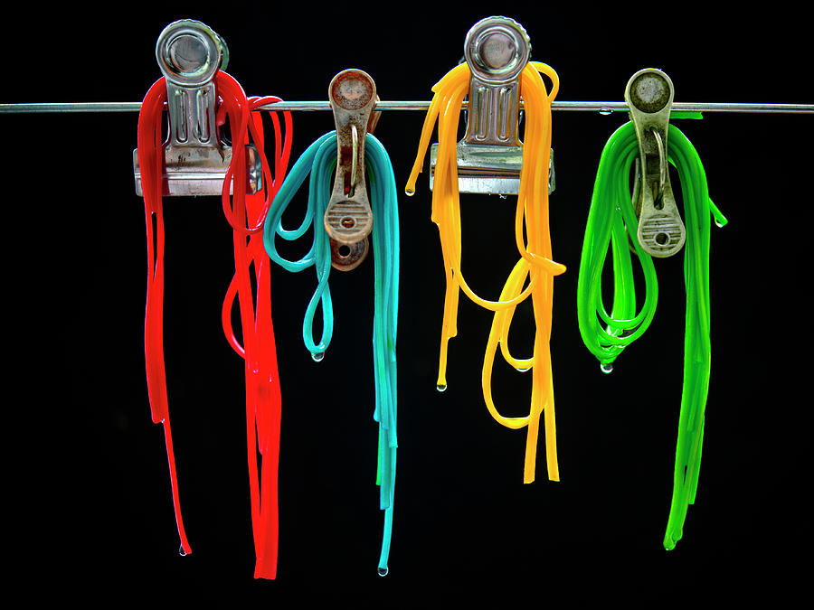 Different Coloured Spaghetti Hung Fom Clips In Front Of A Black Background Photograph by Kaktusfactory