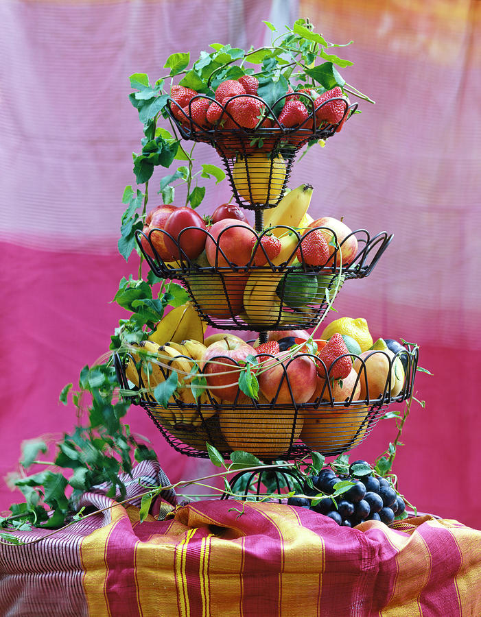 Fruit Photograph - Different Fresh Fruits In Tiered Wire Stand With Tendrils On Table by Jalag / Gtz Schwan