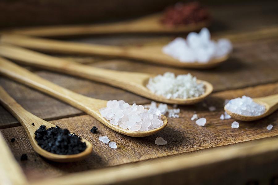 Different Types Of Food Coarse Salt In Wooden Spoons On Dark Background Photograph by Nicole Godt
