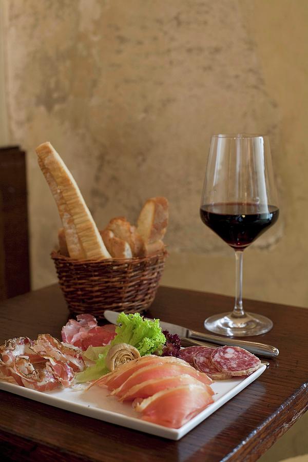 Dish Of Cold Pork Meats , Bread Sticks And A Glass Of Red Wine On A Table In A Restaurant Photograph by Delauw