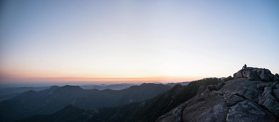 Sequoia National Park Photograph - Distant View Of Man Sitting On Cliff At Sequoia National Park Against Sky During Sunset by Cavan Images