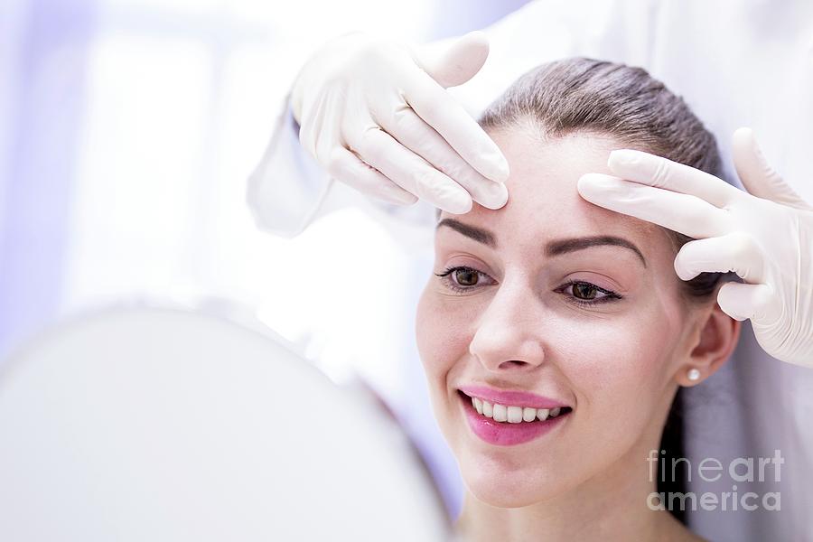 Doctor Examining Young Womans Forehead Photograph by Science Photo Library