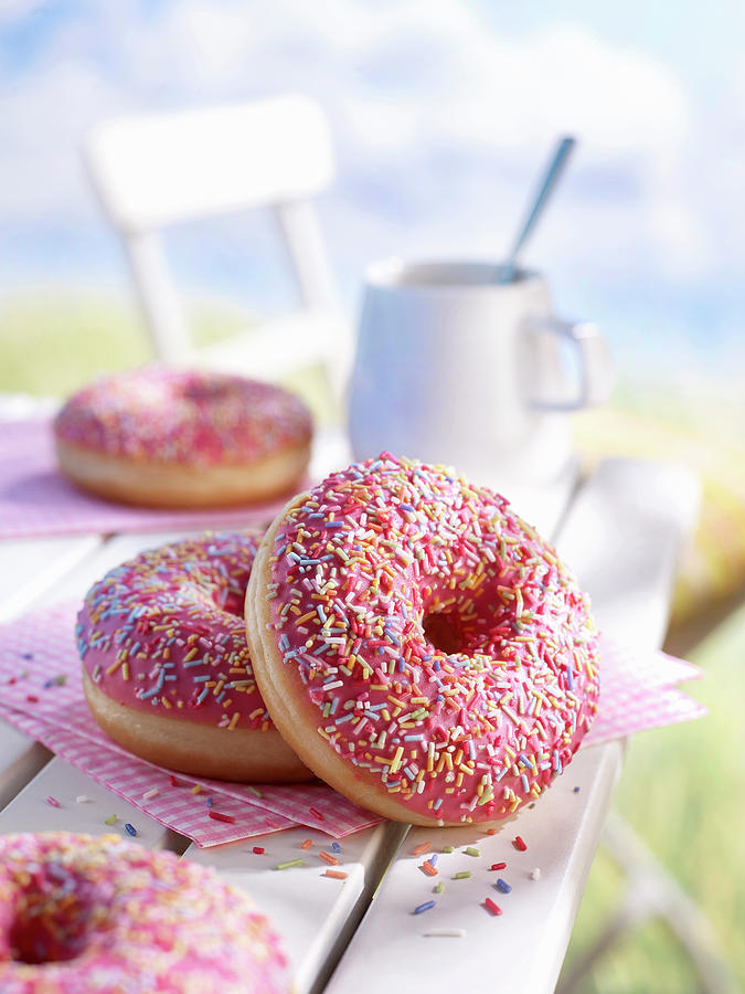 Donuts With Pink Icing And Colorful Sprinkles On A Garden Table Photograph by Frank Gllner