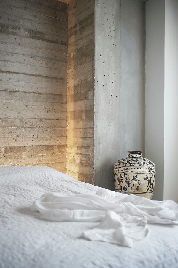 Double Bed With White Bedspread And Urn Against Exposed Concrete Wall Photograph by Alexander Van Berge