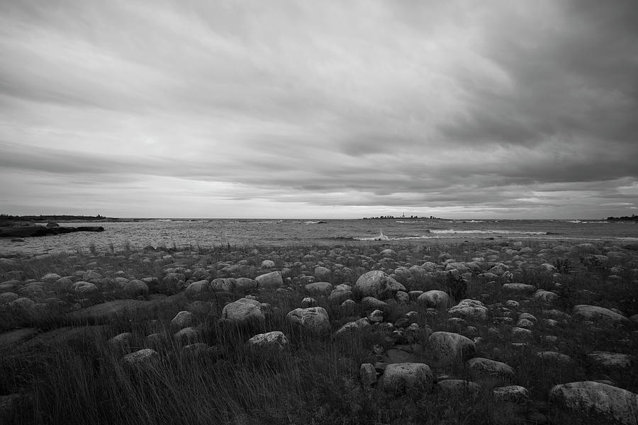 Dramatic Sky Over A Grassy, Stone-strewn Ocean Beach - Monochrome Photograph